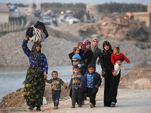 Beberapa wanita bersama anak mereka menuju ke kem pelarian di sempadan. - FOTO: AFP