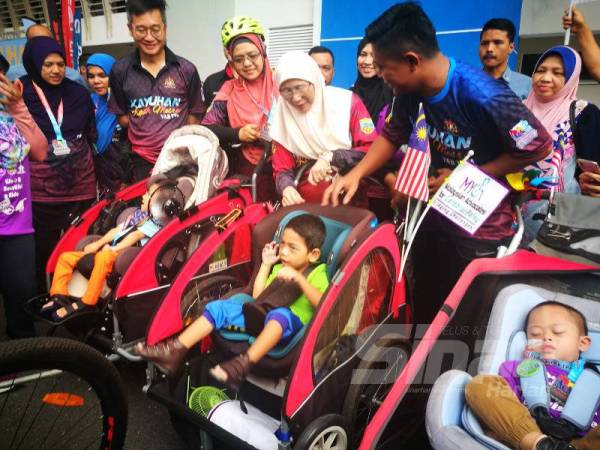 Wan Azizah beramah mesra dengan seorang kanak-kanak kurang upaya pada Program Kayuhan Kasih Mesra di Pandan Perdana hari ini.