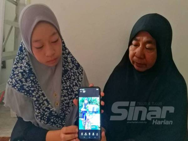 Robiah (kanan) dan kakak kepada Muhammad Danish Erika menunjukkan gambar arwah.