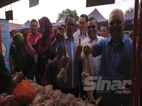 Ishak (kanan) dan Sofi menunjukkan ayam yang dijual murah RM6 seekor pada program Bazar Peduli Rakyat di pekarangan Kompleks JAPERUN Durian Tunggal di sini, hari ini. 