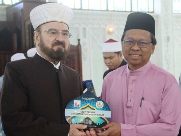 Asmuni menyampaikan cenderahati kepada Dr Ali Muhyiddin.