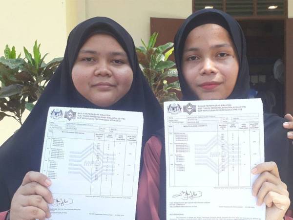 Nur A'dilah (kiri) bersama Nur A'liyah menunjukkan slip STPM 2019 dengan PNGK 4.0 yang diperoleh mereka berdua.