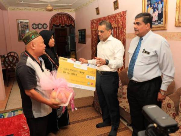 Mohammed Azman (dua dari kanan) menyampaikan cek faedah Perkeso kepada Siti Nur Juliana di Seremban semalam.