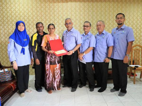 Ismail (tengah) menyerahkan Faedah Pengurusan Mayat dan bayaran pencen Faedah Orang Tanggungan RM837.00 sebulan kepada balu mendiang Subramanian di sini.