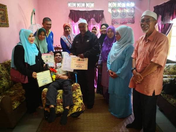 Amir kelihatan gembira bersama sijil kecemerlangan dan bantuan yang diterima.