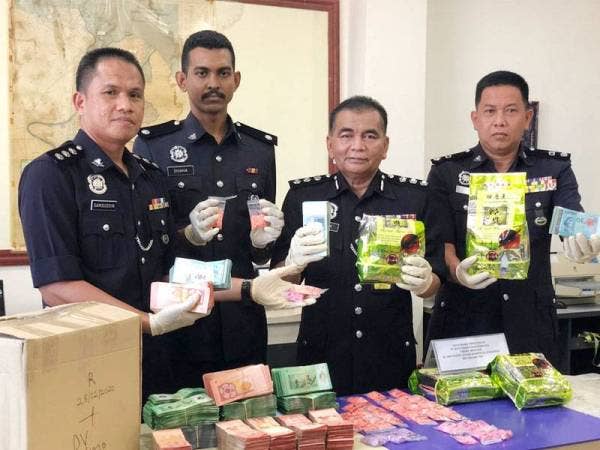 Abdul Rahim (dua dari kanan) menunjukkan dadah dan wang tunai yang dirampas daripada ketiga-tiga suspek dalam serbuan di Kampung Sireh Sabtu lalu.