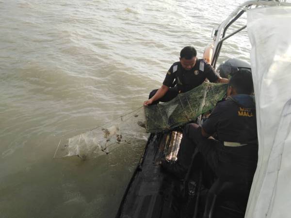 Anggota APMM Zon Kuala Perlis menaikkan bubu naga yang dirampas.