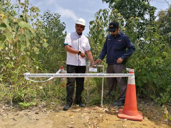 Mohd Fazil (kiri) melihat penyambungan paip secara haram di kebun sayur dekat Kampung Jimah semalam.