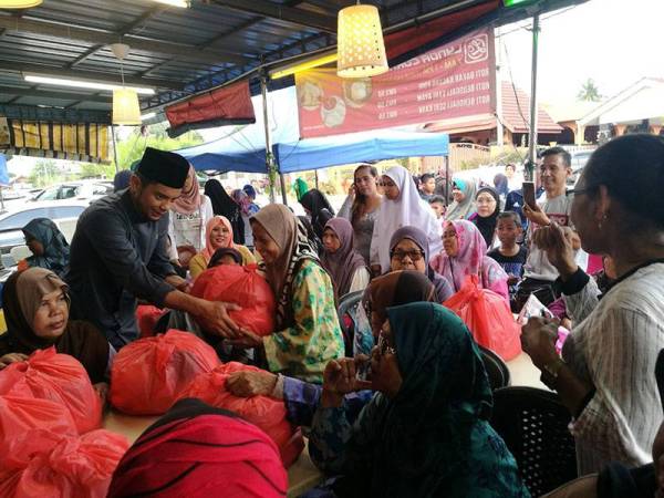 Hasnul Zulkarnain menyampaikan sumbangan kepada penerima bantuan sempena program Sembang Santai @ Tengku Hussein, Manjoi hari ini.