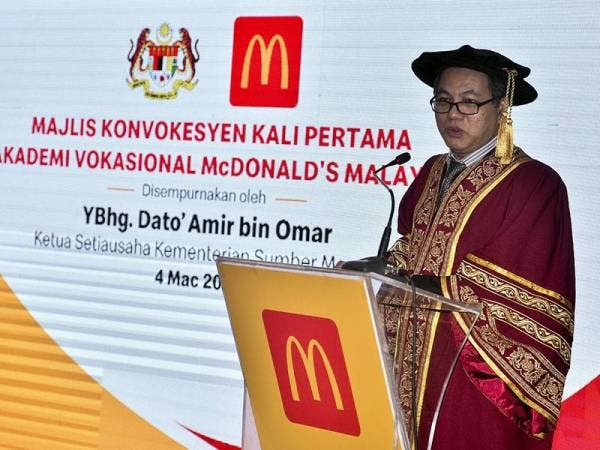 Ketua Setiausaha Kementerian Sumber Manusia Datuk Amir Omar (tengah) menyampaikan Anugerah Graduan Cemerlang kepada Noor Fazriza Fazlin Abdul Rahim (kanan) pada Majlis Konvokesyen Pertama Akademi Vokasional McDonald's Malaysia hari ini. - Foto Bernama