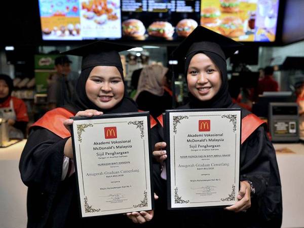 Noor Fazriza Fazlin Abdul Rahim (kanan) dan Nur Aizah Hamdin menunjukkan sijil masing-masing selepas merangkul Anugerah Graduan Cemerlang yang disampaikan oleh Ketua Setiausaha Kementerian Sumber Manusia Datuk Amir Omar pada Majlis Konvokesyen Pertama Akademi Vokasional McDonald's Malaysia hari ini. - Foto Bernama