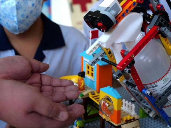 Seorang pelajar menggunakan dispenser disinfektan automatik yang dihasilkan menggunakan Lego di Kaohsiung, Taiwan. - Foto Agensi