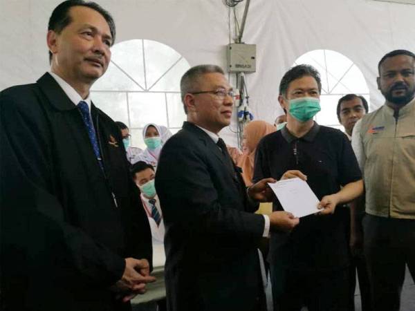 Dr Adham (dua dari kiri) menyerahkan surat pelepasan kepada salah seorang individu yang dikuarantin selama 14 hari di AKEPT selepas dibawa pulang dari Wuhan,China pada 26 Februari lalu.