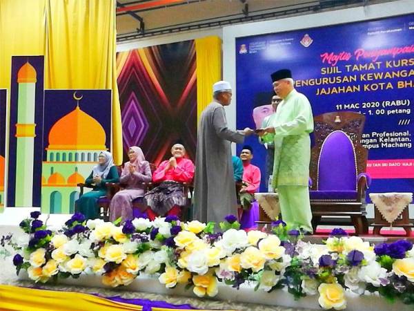 Tengku Mohamad Rizam (kanan) menyampaikan sijil penghargaan kepada peserta kursus pengurusan kewangan masjid di UiTM Cawangan Kelantan di Machang semalam.