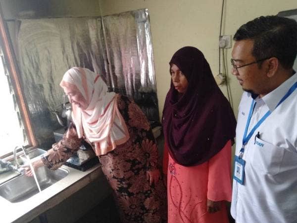 Ahmad Faizal (kanan) bersama Daroyah (kiri) melawat rumah seorang penerima pili cekap air di Klang kelmarin.