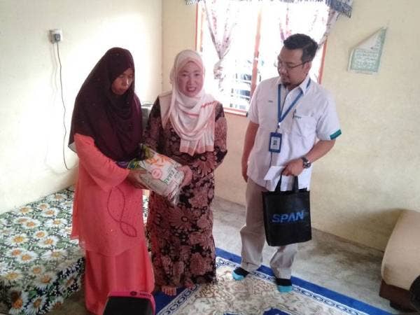 Daroyah (tengah) bersama Ahmad Faizal menyerahkan sumbangan beras kepada penerima.