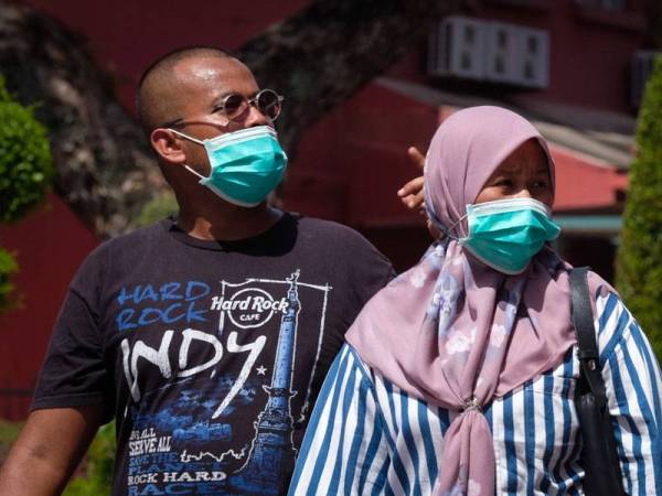 Orang ramai memakai penutup hidung dan mulut sebagai langkah penjegahan susulan penularan COVID-19 ketika tinjauan di sekitar Bandar Hilir hari ini. - Foto Bernama