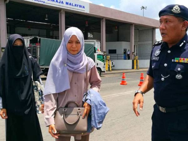 Mohamad Roy (kanan) bertanyakan sesuatu kepada warga Thailand yang keluar dari negeri ini hari ini.