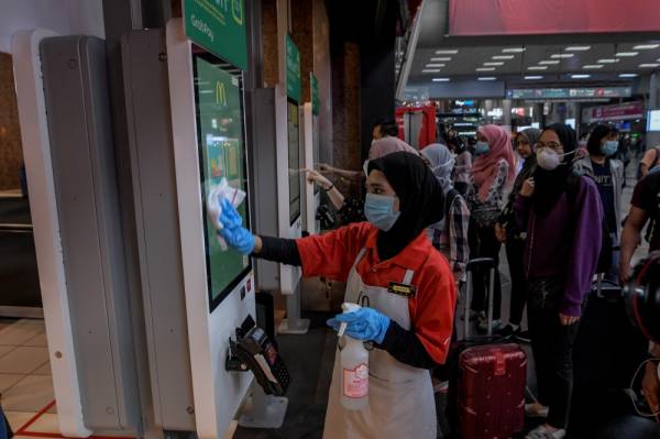 Pekerja restoran makanan segera melakukan pembersihan rutin dengan mengelap skrin pesanan yang digunakan para pelanggan menggunakan cecair pembasmi kuman susulan penularan Covid-19 di negara ini. -Foto Bernama
