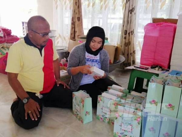 Fatin Nabila Syahira bersama bapanya Alias melihat sebahagian daripada cenderahati yang akan diagihkan kepada tetamu pada hari majlis nanti