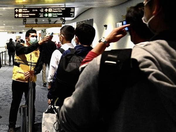 Pihak berkuasa kesihatan Indonesia memeriksa suhu tubuh penumpang yang tiba di Lapangan Terbang Antarabangsa Jakarta. - Foto AFP