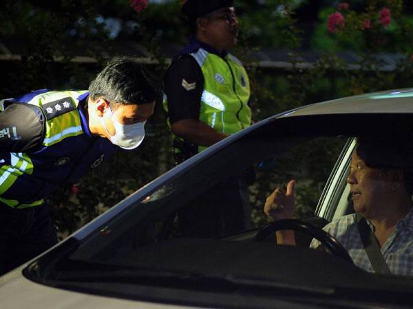 Pegawai polis menasihatkan pengguna jalan raya supaya mengambil serius tindakan kerajaan atas pelaksanaan Perintah Kawalan Pergerakan yang bermula hari ini sehingga 31 Mac sebagai langkah mengekang penularan jangkitan COVID-19 ketika Ops COVID-19 di Jalan Khoo Kai Kim, malam ini. - Foto Bernama