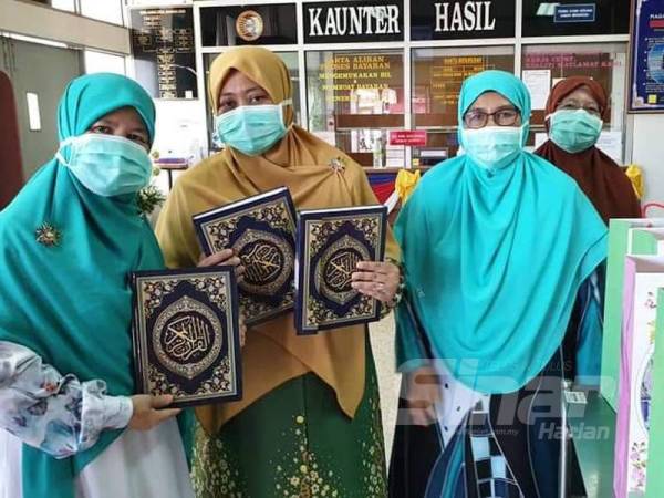 Zuraida (dua, kiri) ketika menyerahkan al-Quran kepada pesakit yang dikuarantin di Hospital Hulu Terengganu akibat penularan wabak Covid-19.