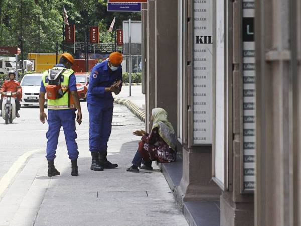 Kelihatan Anggota Jabatan Pertahanan Awam Malaysia (JPAM) memberi nasihat kepada orang awam ketika melakukan penguatkuasaan Perintah Kawalan Pergerakan ketika tinjauan di ibu kota hari ini. - Foto Bernama
