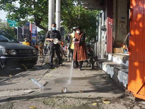 Bu Risma sedang bersihkan kaki lima di hadapan sebuah premis di Surabaya.- Foto: Bangga Surabaya