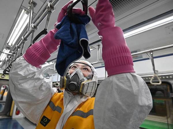 Langkah nyahjangkit dilakukan di sebuah kereta api untuk membendung penularan Covid-19 di Seoul. - Foto AFP