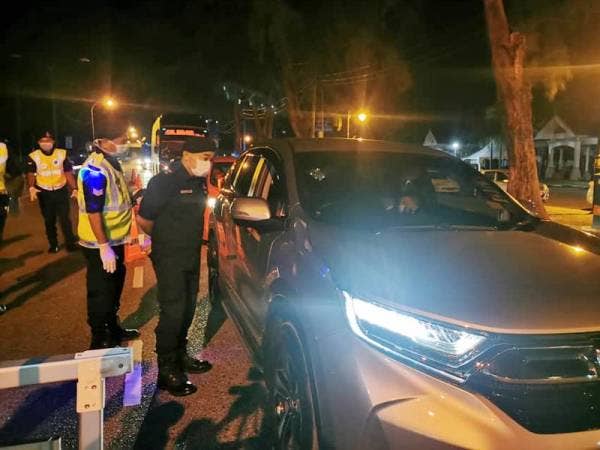 Anggota bertugas dalam sekatan jalan raya sempena Perintah Kawalan Pergerakan memberi nasihat kepada pemilik kenderaan yang ditahan dalam sekatan di Plaza Padang Negara, Jalan Batu Buruk, di sini, malam tadi