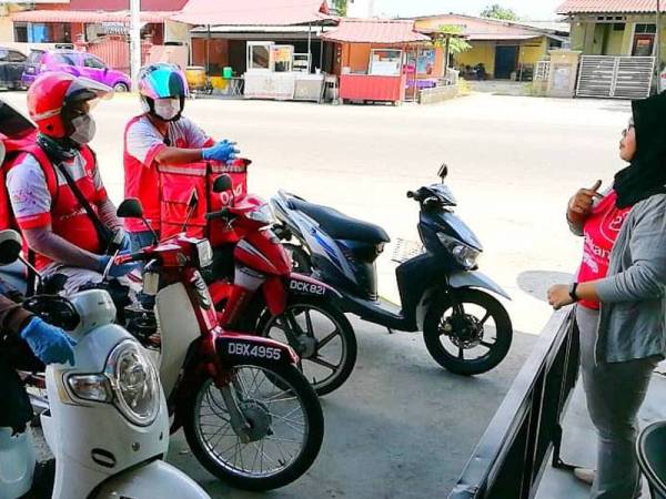 Umairah (kanan) memberikan arahan kepada pekerja penghantar makanan di bawah Syarikat OdaMakan sebelum mereka memulakan tugas.