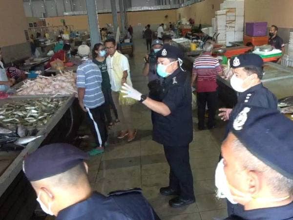 Roslee (tengah) menasihatkan orang ramai dan peniaga di Pasar Payang hari ini.