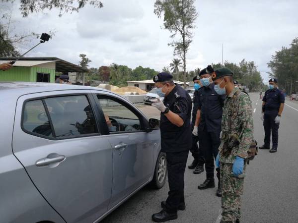 Roslee (kiri) sewaktu membuat pemantauan Perintah Kawalan Pergerakan di Kelulut, Marang di sini hari ini