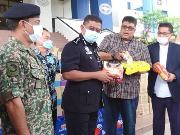 Mat Kasim (dua dari kiri) ketika menerima sumbangan makanan daripada Umno negeri yang diketuai Sulaiman (kanan) dan Rauf (dua,kanan) di Ibu pejabat Polis Kontinjen Melaka (IPK) di Bukit Beruang di sini, hari ini.