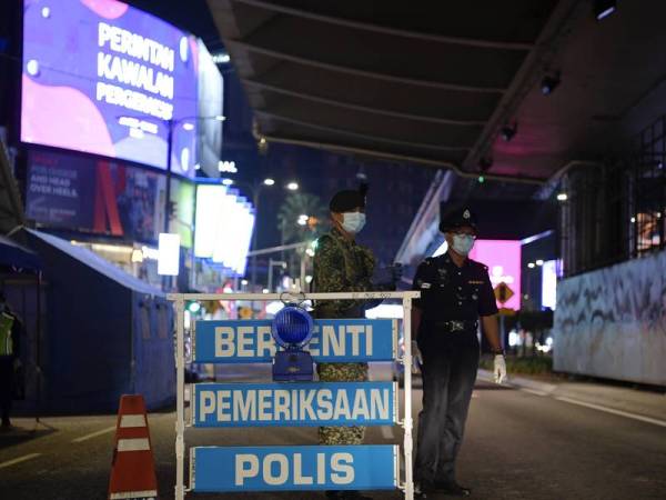 Anggota polis dan tentera bekerjasama melakukan sekatan jalan raya susulan Perintah Kawalan Pergerakan selama 14 hari sehingga 31 Mac ini ketika tinjauan di sekitar ibu kota malam tadi. - Foto Bernama