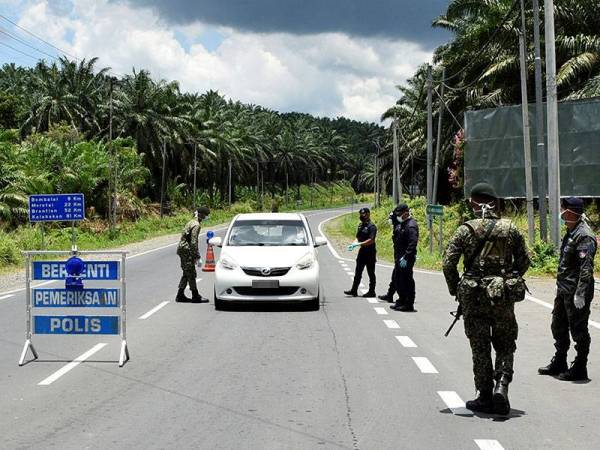 Kelihatan anggota keselamatan menanyakan sesuatu kepada seorang pemandu yang menuju ke pusat bandar pada sekatan Jalan Raya di Kilometer 10 Jalan Kuhara-Jembatan Putih. -Foto Bernama