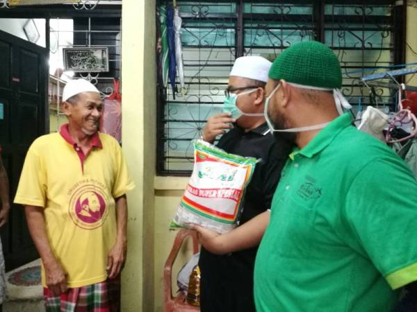Pasukan sukarelawan Masjid Sultan Azlan Shah diketuai Syed Mohd Muzaffar (dua dari kanan) menyampaikan sumbangan kepada mereka yang terjejas kesan pelaksanaan PKP.