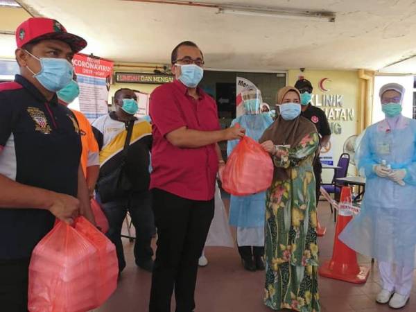 Mohd Rafiq (Tengah) menyampaikan sumbangan makanan kepada wakil Klinik KesihataN Cheng, di sini, hari ini.