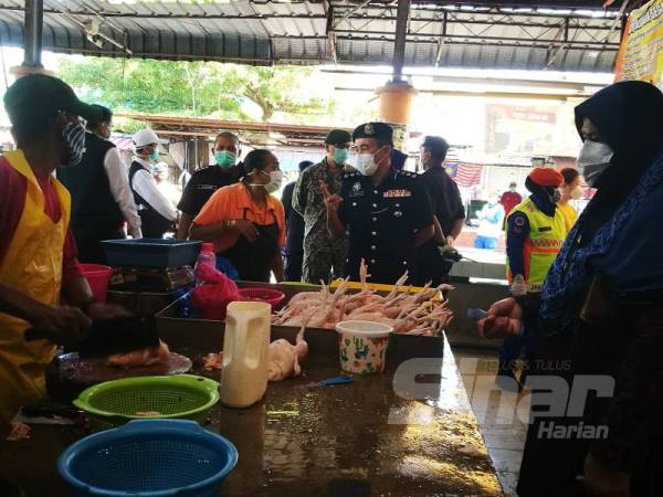 Adzli (dua kanan) memantau aktiviti penjualan di pasar awam Taman Keladi hari ini.