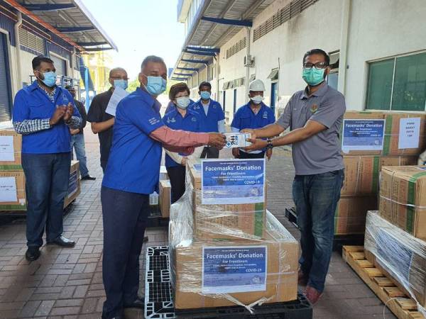 Selvakumar (kiri) menyampaikan sumbangan topeng muka kepada wakil Jabatan Imigresen