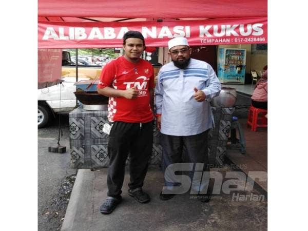 Muhammad Afzan (kiri) di hadapan gerainya yang menjual nasi kukus di Dataran Otomobil, Seksyen 15, Shah Alam.