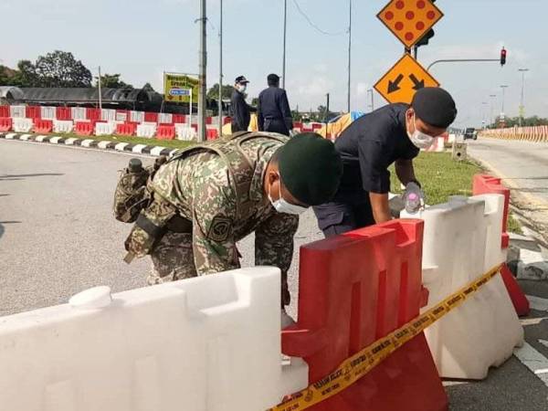 Anggota Polis Diraja Malaysia dan Angkatan Tentera Malaysia sedang menyusun penghadang jalan.