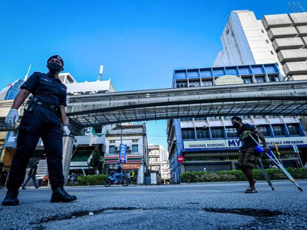 Anggota keselamatan mengawal pergerakan orang ramai ketika tinjauan Perintah Kawalan Pergerakan (PKP) di sekitar Jalan Chow Kit hari ini. - Foto Bernama