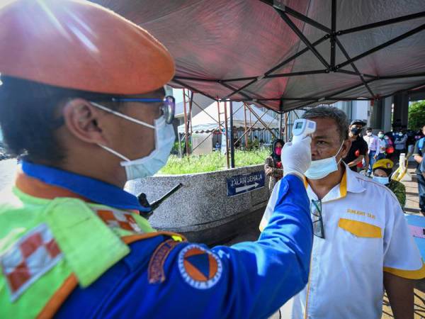 Anggota keselamatan memeriksa suhu badan orang ramai ketika beratur untuk membeli barang keperluan di Pasar Raja Bot ketika tinjauan di sekitar Jalan Chow Kit hari ini. - Foto Bernama