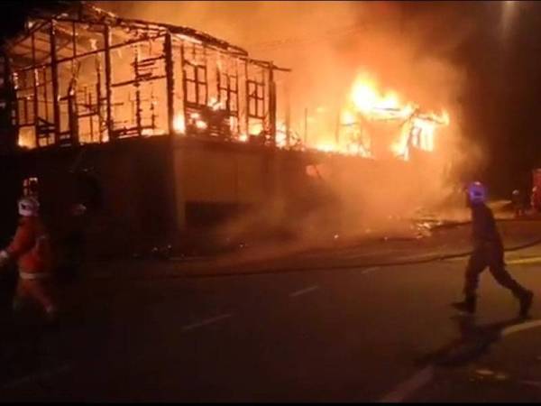 Anggota bomba menjalankan operasi pemadaman membabitkan 11 kedai di Behrang Stesen.