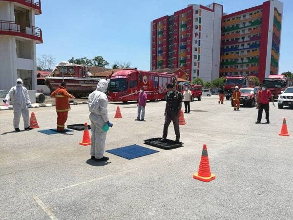 Petugas Operasi Sanitasi Awam Covid-19 menjalani proses nyah cemar di Balai Bomba dan Penyelamat Indera Mahkota selepas selesai operasi di sekitar bandar Kuantan dan Indera Mahkota di sini, hari ini.