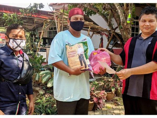 Mangsa ribut (tengah) menerima sumbangan beras daripada kerajaan negeri yang disampaikan oleh wakil kawasan masing-masing.