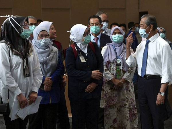 Perdana Menteri Tan Sri Muhyiddin Yassin (kanan) berjumpa dengan para petugas barisan hadapan Kementerian Kesihatan Malaysia (KKM) semasa melakukan tinjauan kerja-kerja menyiapkan Pusat Kuarantin dan Rawatan COVID-19 Berisiko Rendah di Taman Ekspo Pertanian Malaysia Serdang (MAEPS) hari ini. - Foto Bernama