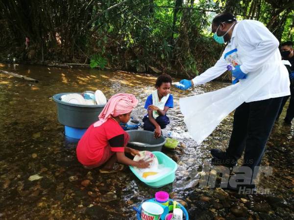 Abdul Azeez memantau keadaan anak orang asli yang sedang mencuci pinggan mangkuk di tepi sungai. 